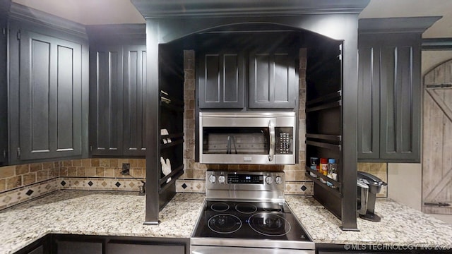 6166 Hedges St, Ardmore, OK 73401 - kitchen with appliances with stainless steel finishes, tasteful backsplash, and light stone counters