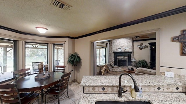6166 Hedges St, Ardmore, OK 73401 - kitchen featuring ornamental molding, a stone fireplace, a textured ceiling, light tile patterned floors, and light stone counters