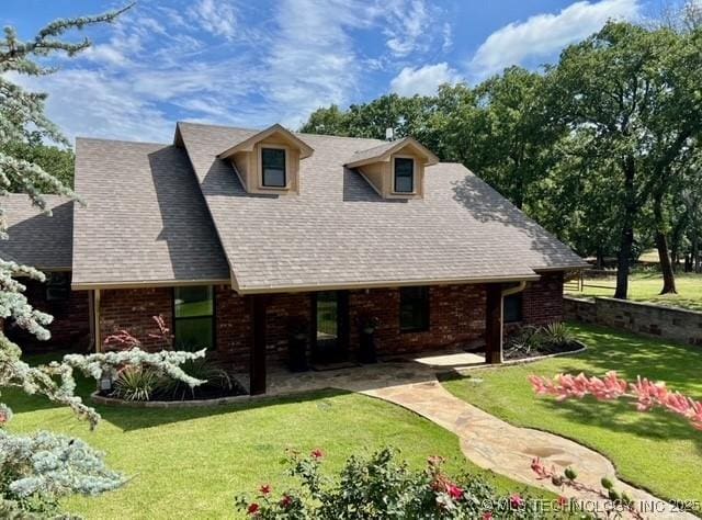 6166 Hedges St, Ardmore, OK 73401 - cape cod home with a front lawn, brick siding, roof with shingles, and a patio area