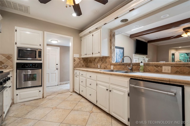 213 Moccasin Ln, Sapulpa, OK 74066 - kitchen with appliances with stainless steel finishes, ceiling fan, backsplash, white cabinetry, and ornamental molding