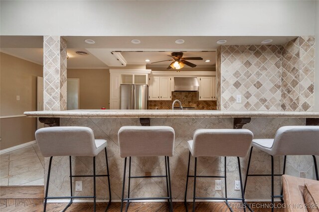 213 Moccasin Ln, Sapulpa, OK 74066 - kitchen featuring freestanding refrigerator, ornamental molding, extractor fan, a kitchen bar, and ceiling fan