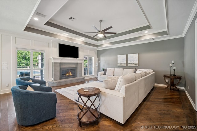 12828 S Mingo Rd, Bixby, OK 74008 - living room featuring ornamental molding, a ceiling fan, a raised ceiling, a brick fireplace, and dark wood-style floors