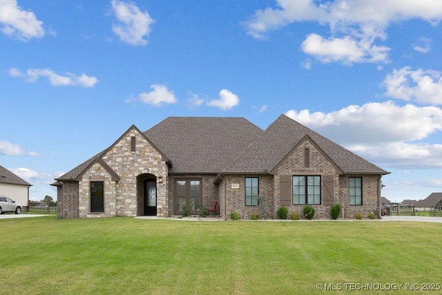 8337 N 149th E Ave, Owasso, OK 74055 - french country style house featuring a front yard, brick siding, and a shingled roof