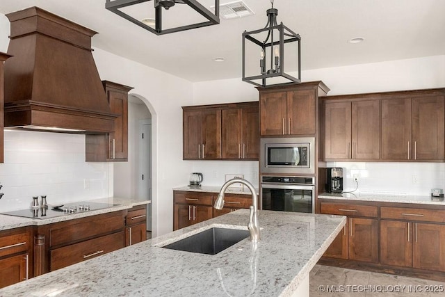 8337 N 149th E Ave, Owasso, OK 74055 - kitchen with stainless steel appliances, custom range hood, tasteful backsplash, and arched walkways