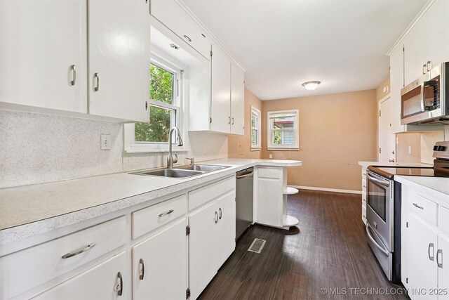 1422 E 52nd St, Tulsa, OK 74105 - kitchen with stainless steel appliances, plenty of natural light, dark wood-style floors, and light countertops