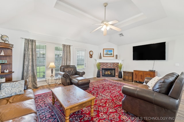 1014 W 120th St S, Jenks, OK 74037 - living room with ceiling fan, wood finished floors, a brick fireplace, a tray ceiling, and vaulted ceiling
