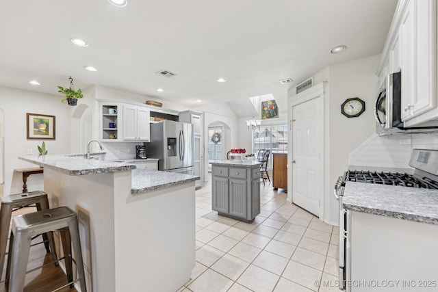 1014 W 120th St S, Jenks, OK 74037 - kitchen with stainless steel appliances, tasteful backsplash, a peninsula, a kitchen bar, and open shelves
