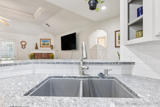 1014 W 120th St S, Jenks, OK 74037 - kitchen with backsplash, light stone countertops, vaulted ceiling, ceiling fan, and white cabinetry