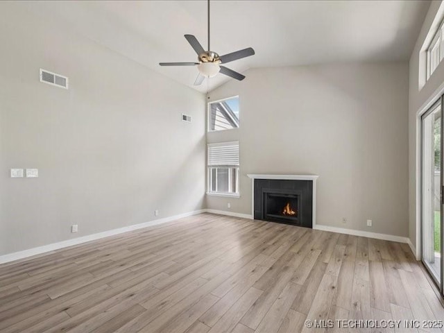9118 S Florence Ave Unit 9118, Tulsa, OK 74137 - unfurnished living room featuring high vaulted ceiling, light wood-style floors, healthy amount of natural light, a ceiling fan, and a lit fireplace