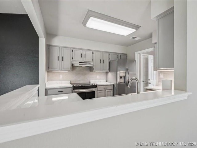 9118 S Florence Ave Unit 9118, Tulsa, OK 74137 - kitchen with stainless steel appliances, under cabinet range hood, light countertops, backsplash, and gray cabinetry
