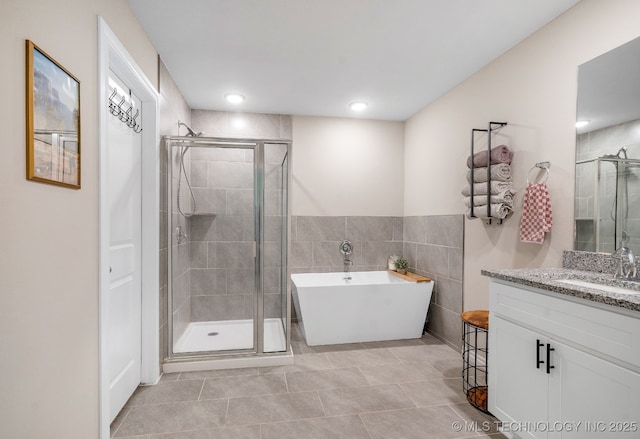 7245 E 154th St S, Bixby, OK 74008 - bathroom with a stall shower, a freestanding bath, vanity, tile walls, and tile patterned flooring