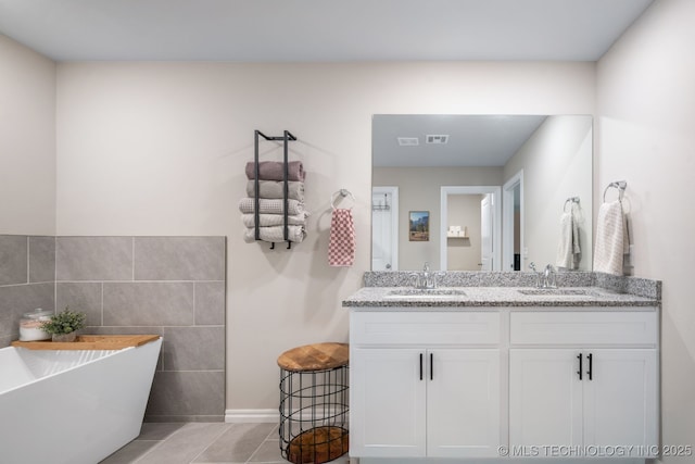 7245 E 154th St S, Bixby, OK 74008 - bathroom with double vanity, tile patterned flooring, a soaking tub, and tile walls