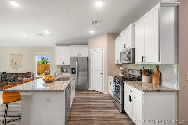7245 E 154th St S, Bixby, OK 74008 - kitchen featuring appliances with stainless steel finishes, dark wood-style floors, backsplash, white cabinetry, and a breakfast bar area