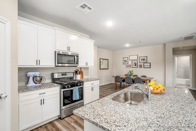 7245 E 154th St S, Bixby, OK 74008 - kitchen with appliances with stainless steel finishes, light wood-style floors, tasteful backsplash, white cabinetry, and light stone counters