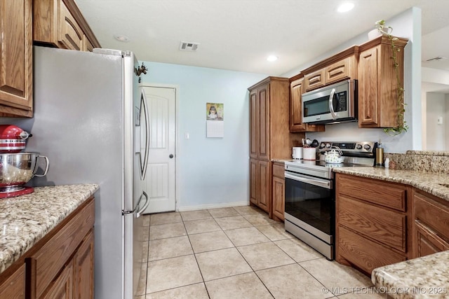 545 E 498th Cir, Pryor, OK 74361 - kitchen with appliances with stainless steel finishes, brown cabinets, light tile patterned flooring, light stone countertops, and recessed lighting
