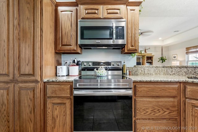 545 E 498th Cir, Pryor, OK 74361 - kitchen with appliances with stainless steel finishes, tile patterned flooring, light stone countertops, and brown cabinetry