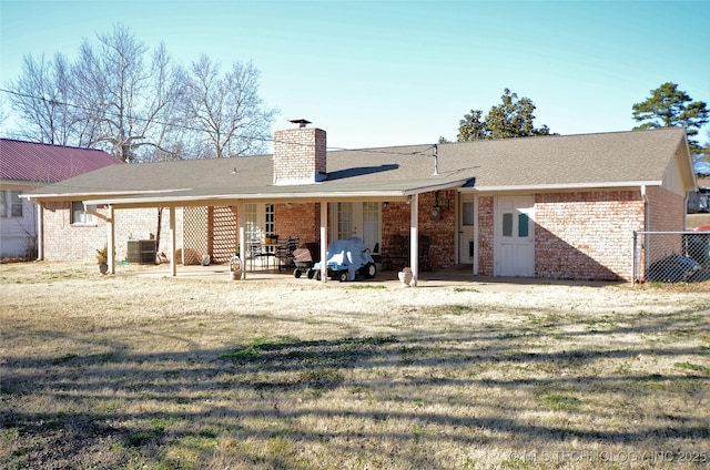 236 W 7th Ave, Bristow, OK 74010 - rear view of house with a chimney, brick siding, and a patio