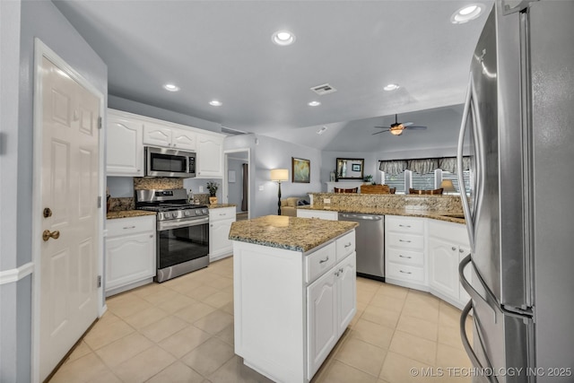 19722 E 50th Ct S, Broken Arrow, OK 74014 - kitchen with stainless steel appliances, a peninsula, a center island, a ceiling fan, and light stone countertops