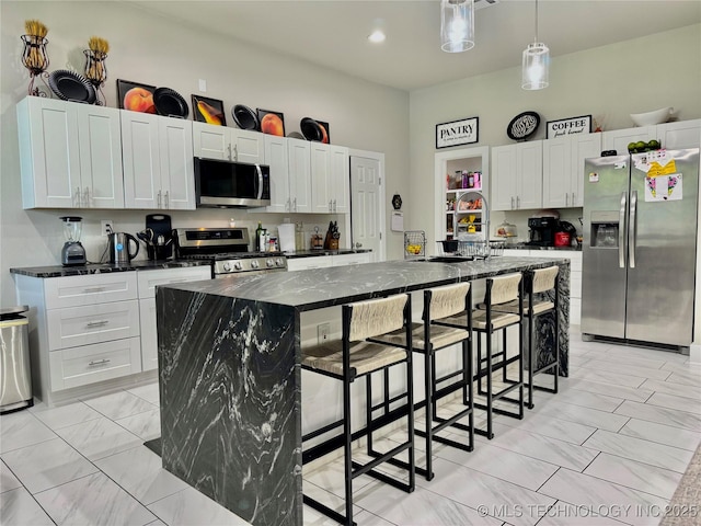 3309 S 116th E Pl, Tulsa, OK 74146 - kitchen featuring appliances with stainless steel finishes, a large island, white cabinets, a breakfast bar area, and decorative light fixtures