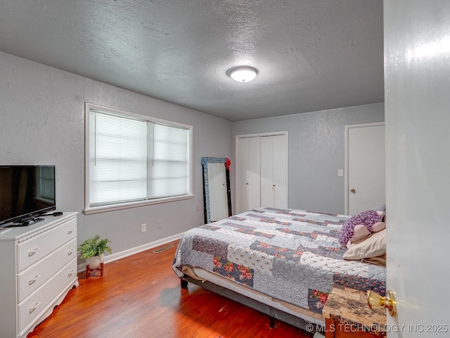 825 W 22nd St, Ada, OK 74820 - bedroom with light wood finished floors, a textured ceiling, a textured wall, and a closet