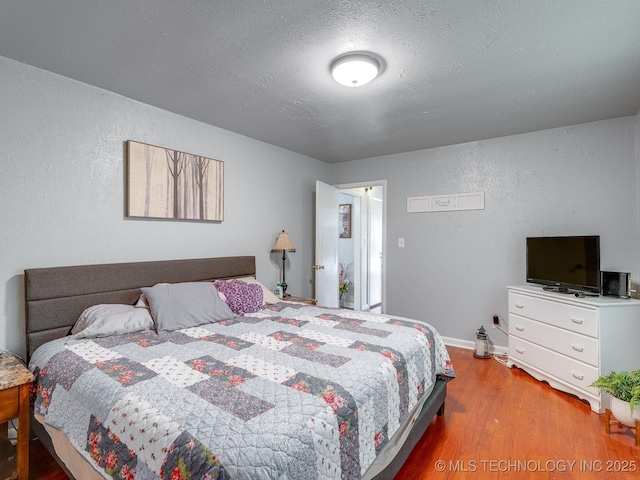825 W 22nd St, Ada, OK 74820 - bedroom featuring a textured wall, wood finished floors, and a textured ceiling