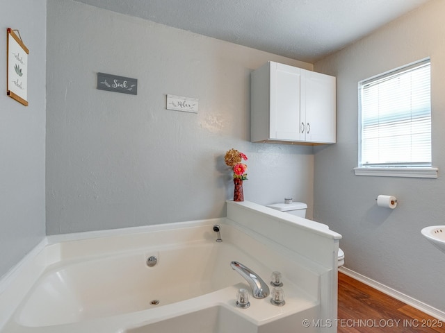 825 W 22nd St, Ada, OK 74820 - bathroom featuring a garden tub and wood finished floors
