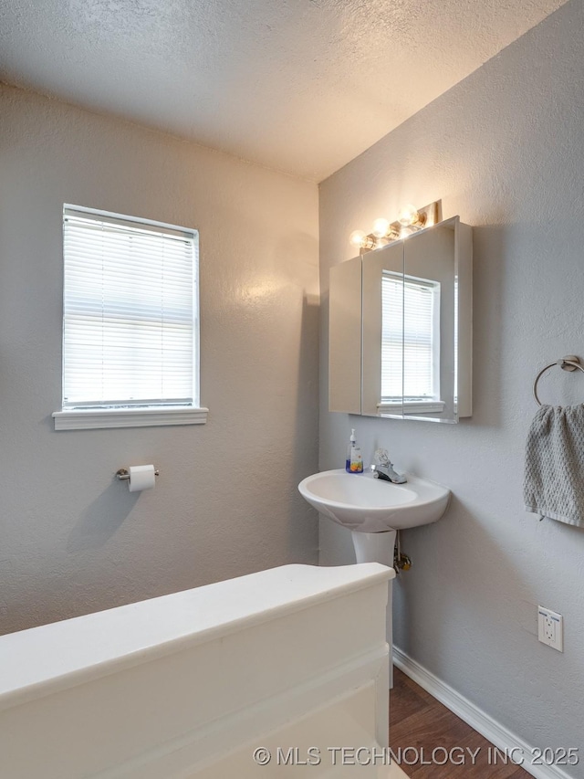 825 W 22nd St, Ada, OK 74820 - bathroom featuring baseboards and wood finished floors