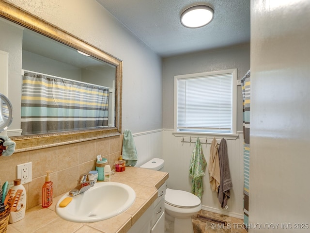 825 W 22nd St, Ada, OK 74820 - bathroom featuring vanity, wainscoting, and a textured ceiling