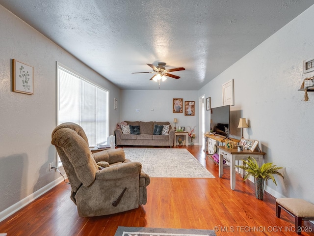 825 W 22nd St, Ada, OK 74820 - living room featuring wood finished floors, a ceiling fan, a textured wall, and a textured ceiling