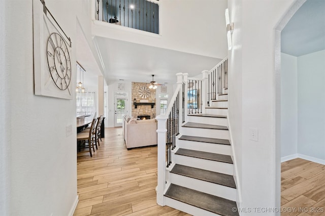 16410 E 49th St, Tulsa, OK 74134 - stairs featuring a ceiling fan, a fireplace, wood finished floors, arched walkways, and a high ceiling