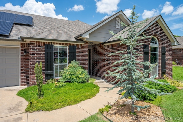 20409 E 49th St S, Broken Arrow, OK 74014 - view of front facade featuring brick siding, roof mounted solar panels, an attached garage, and a shingled roof