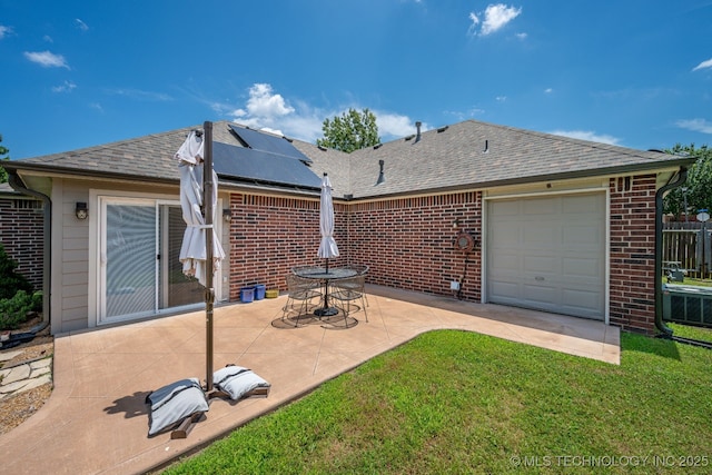 20409 E 49th St S, Broken Arrow, OK 74014 - rear view of house featuring roof with shingles, brick siding, roof mounted solar panels, a yard, and a patio area