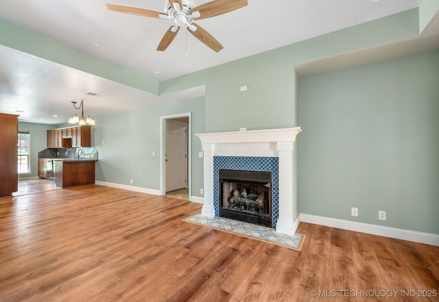 20409 E 49th St S, Broken Arrow, OK 74014 - unfurnished living room featuring a ceiling fan, a fireplace, light wood-style flooring, and a chandelier