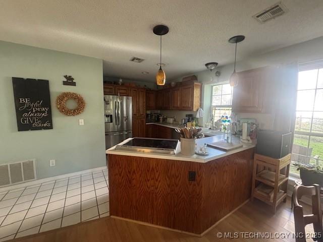 7412 W 38th St, Tulsa, OK 74107 - kitchen featuring stainless steel fridge with ice dispenser, a peninsula, plenty of natural light, and decorative light fixtures