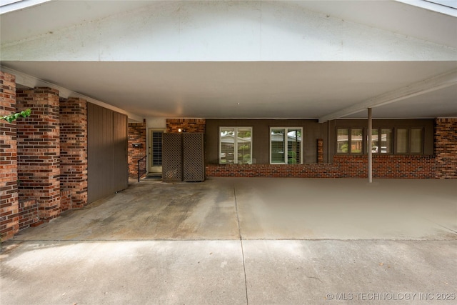 unfurnished living room with brick wall, vaulted ceiling, and concrete floors