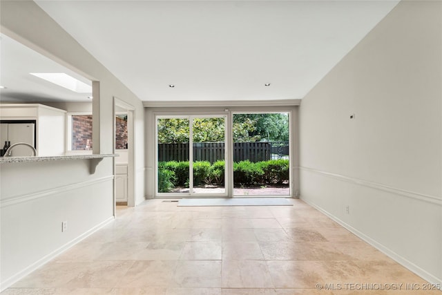 unfurnished room with a skylight and baseboards