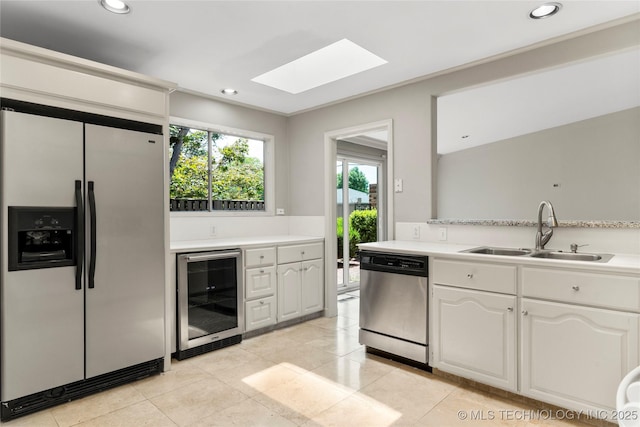 kitchen featuring stainless steel appliances, beverage cooler, a skylight, light countertops, and recessed lighting