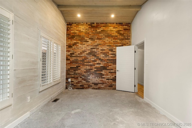 spare room featuring brick wall and wooden ceiling