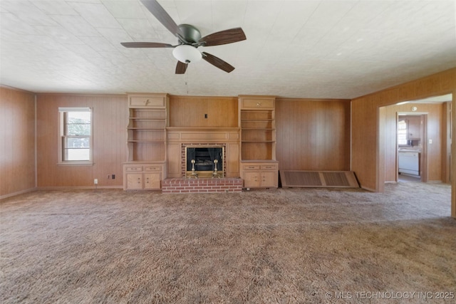 522 E 6th St, Claremore, OK 74017 - unfurnished living room with wood walls, healthy amount of natural light, carpet, ceiling fan, and a fireplace