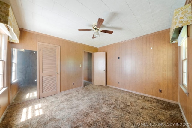 522 E 6th St, Claremore, OK 74017 - unfurnished bedroom with multiple windows, carpet flooring, wooden walls, crown molding, and a ceiling fan