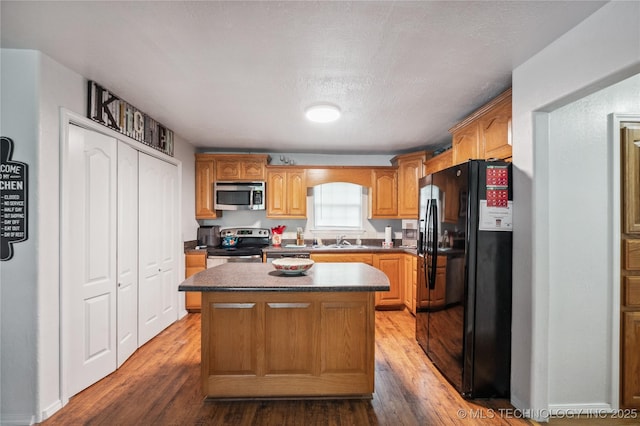1105 S Maple Ave, Tahlequah, OK 74464 - kitchen featuring appliances with stainless steel finishes, dark countertops, a kitchen island, and wood finished floors