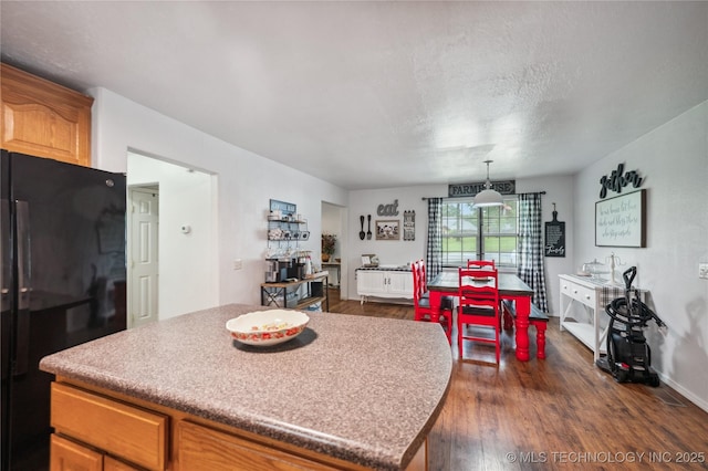 1105 S Maple Ave, Tahlequah, OK 74464 - kitchen with freestanding refrigerator, dark wood-style floors, a center island, light countertops, and a textured ceiling