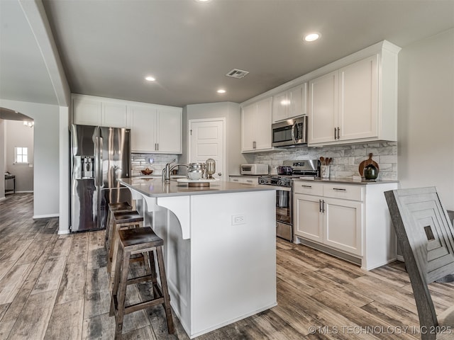 2008 E Union St, Broken Arrow, OK 74011 - kitchen featuring stainless steel appliances, wood finished floors, an island with sink, decorative backsplash, and recessed lighting