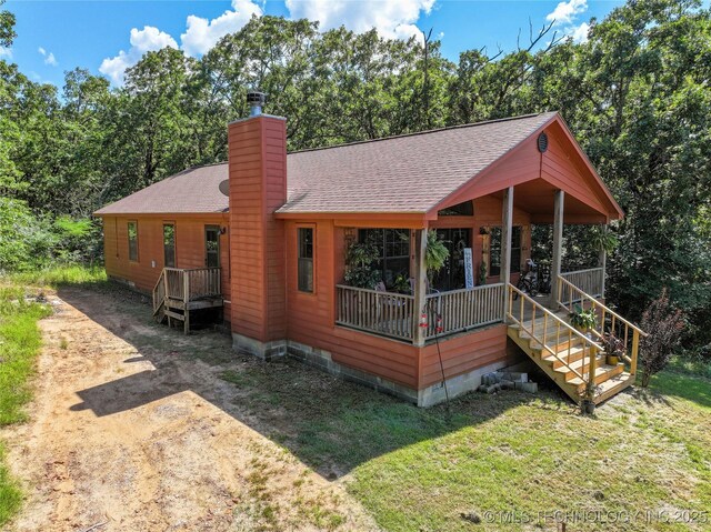 14629 E 233rd St S, Webbers Falls, OK 74470 - view of front of property with a shingled roof, covered porch, a chimney, a front lawn, and view of wooded area