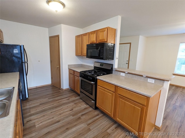 1114 W 22nd St, Claremore, OK 74017 - kitchen with stainless steel appliances, light wood finished floors, a peninsula, light countertops, and brown cabinets