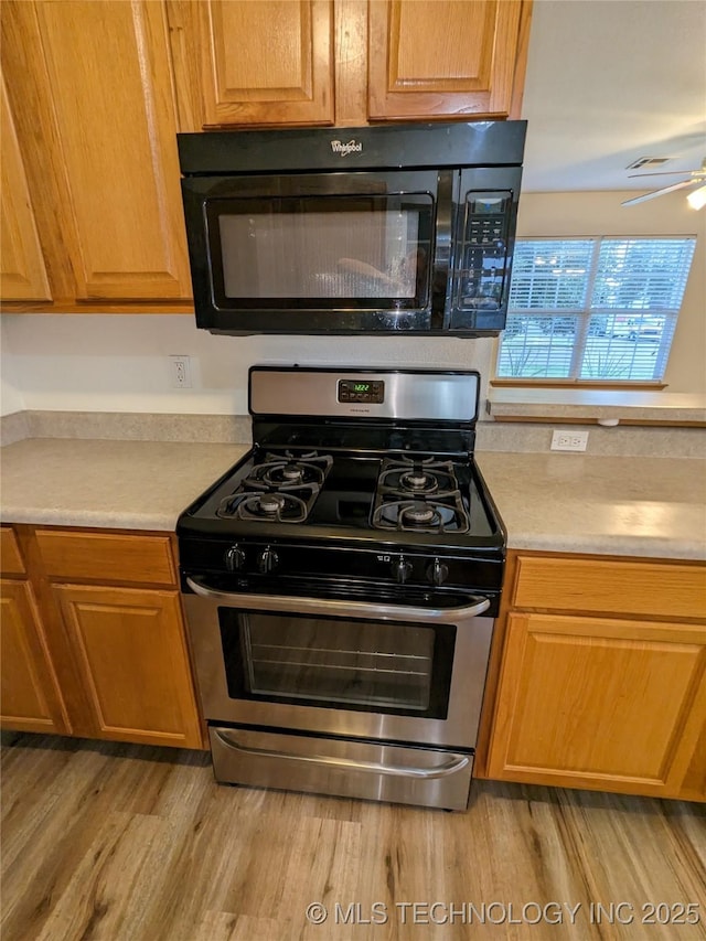 1114 W 22nd St, Claremore, OK 74017 - kitchen with black microwave, stainless steel range with gas stovetop, a ceiling fan, and light countertops