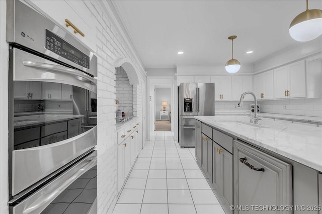 5824 S Louisville Ave, Tulsa, OK 74135 - kitchen featuring appliances with stainless steel finishes, hanging light fixtures, white cabinetry, light stone countertops, and decorative backsplash