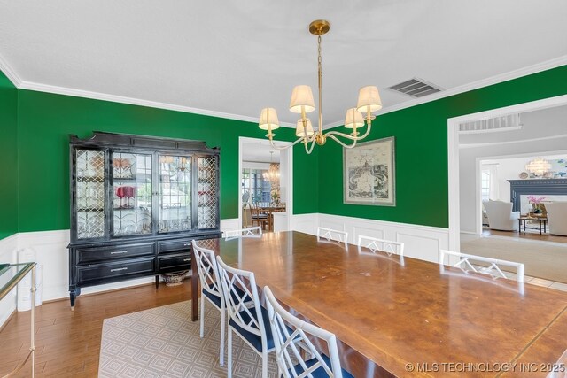 5824 S Louisville Ave, Tulsa, OK 74135 - dining space with a chandelier, ornamental molding, wainscoting, wood finished floors, and a decorative wall
