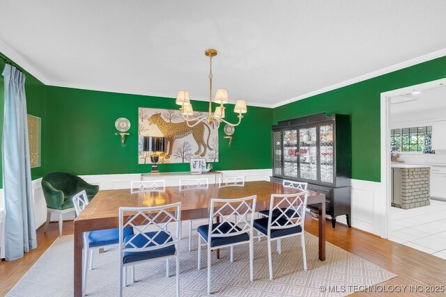 5824 S Louisville Ave, Tulsa, OK 74135 - dining area featuring a chandelier, a wainscoted wall, wood finished floors, ornamental molding, and a decorative wall