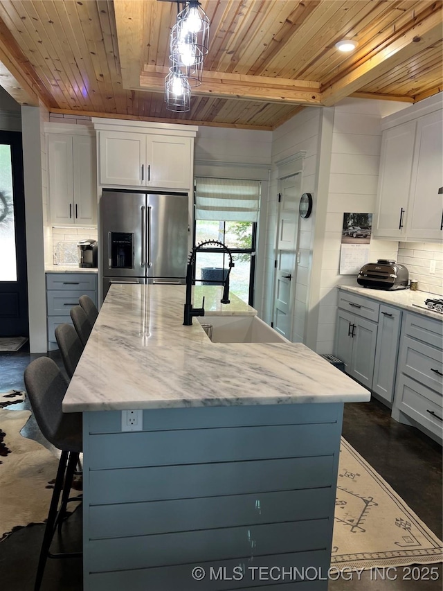 13425 SW 1025th Ave, Tuskahoma, OK 74571 - kitchen with stainless steel fridge, wooden ceiling, a breakfast bar, decorative backsplash, and light stone countertops